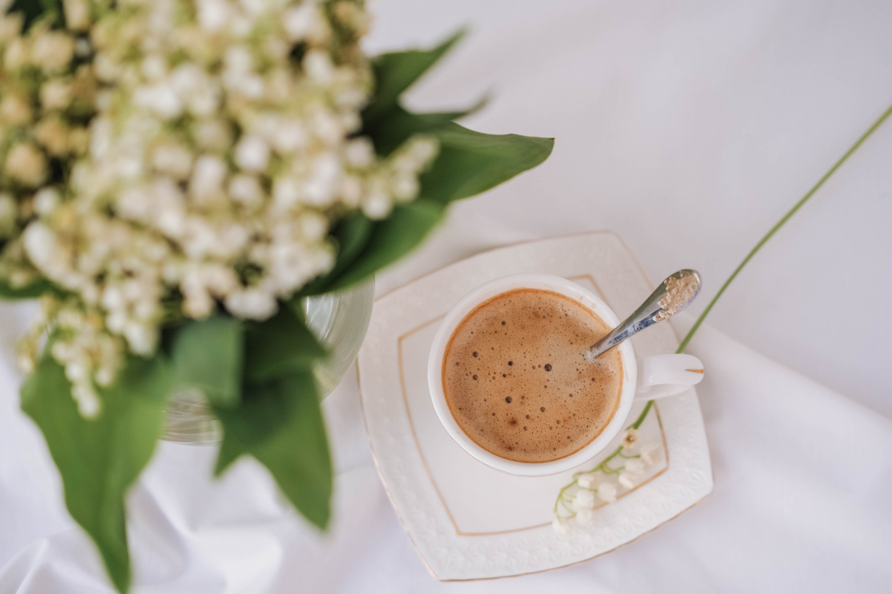 White flowers Lilies of the valley and a cup of coffee
